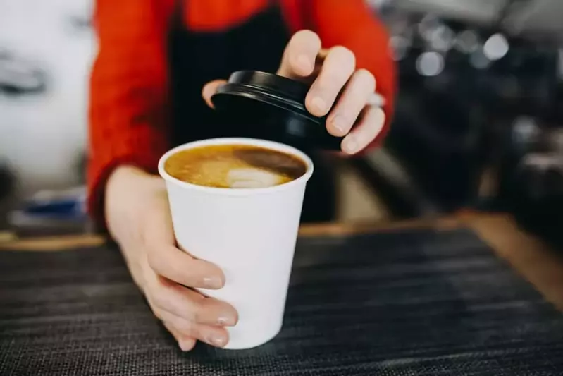 barista putting lid on cup of coffee